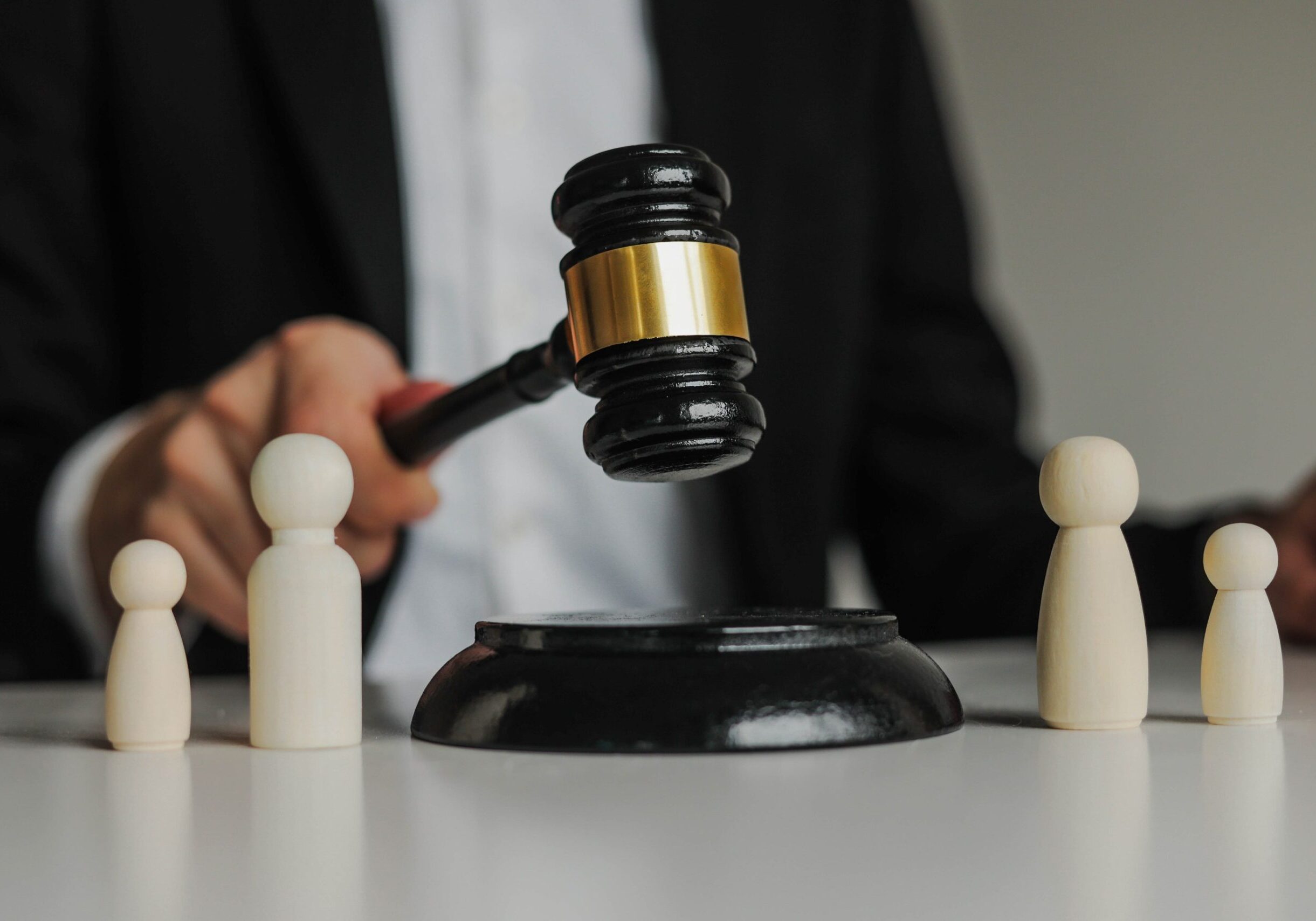 Judge's gavel with wooden figures on table.